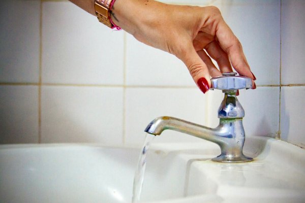 Mulher abrindo a torneira para sair água