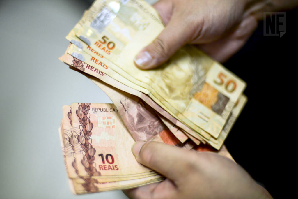 Pessoa manipulando cédulas de dinheiro