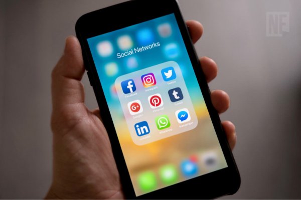 Segurando smartphone exibindo apps de redes sociais