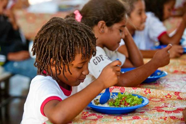 Criança fazendo refeição em escola pública