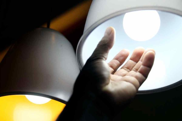 Pessoa mexendo em lustre para troca de lâmpada