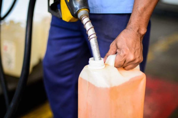 Frentista de posto de combustível enchendo galão com gasolina