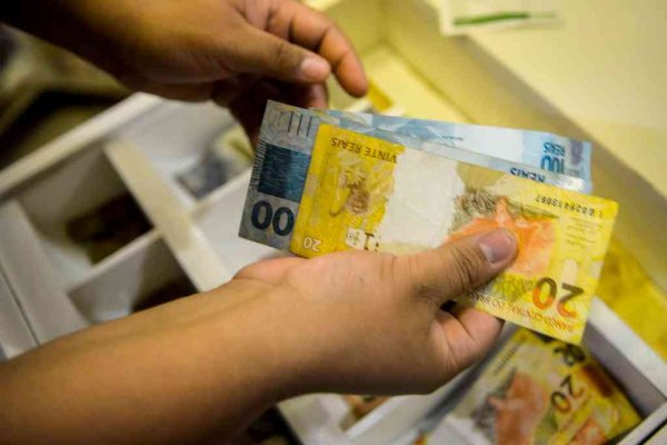 Pessoa manejando dinheiro em caixa registradora de estabelecimento