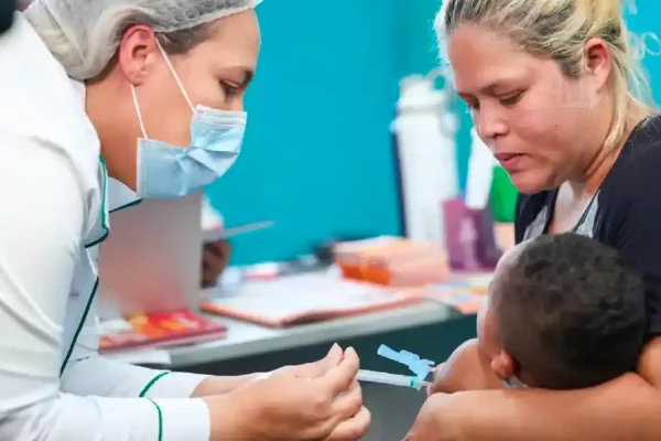 Criança sendo vacinada nos braços da mãe