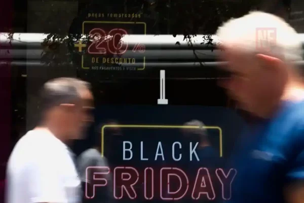 Pessoas passando em frente à loja com anúncio da Black Friday