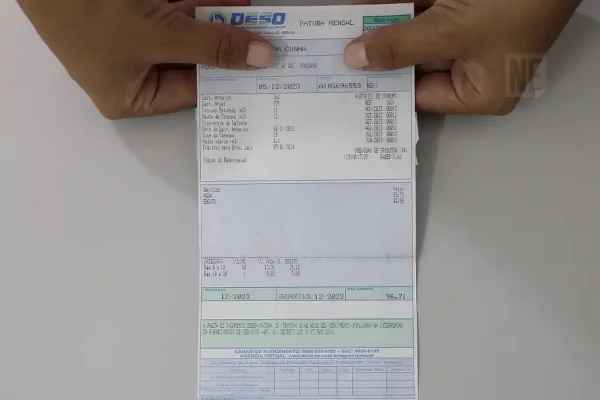 Uma pessoas segurando a conta de água da Deso