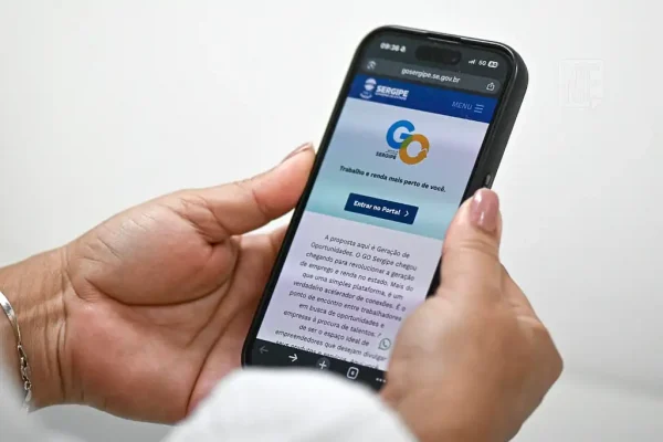 Pessoa segurando o celular com as duas mãos, enquanto a plataforma GO Sergipe aparece na tela