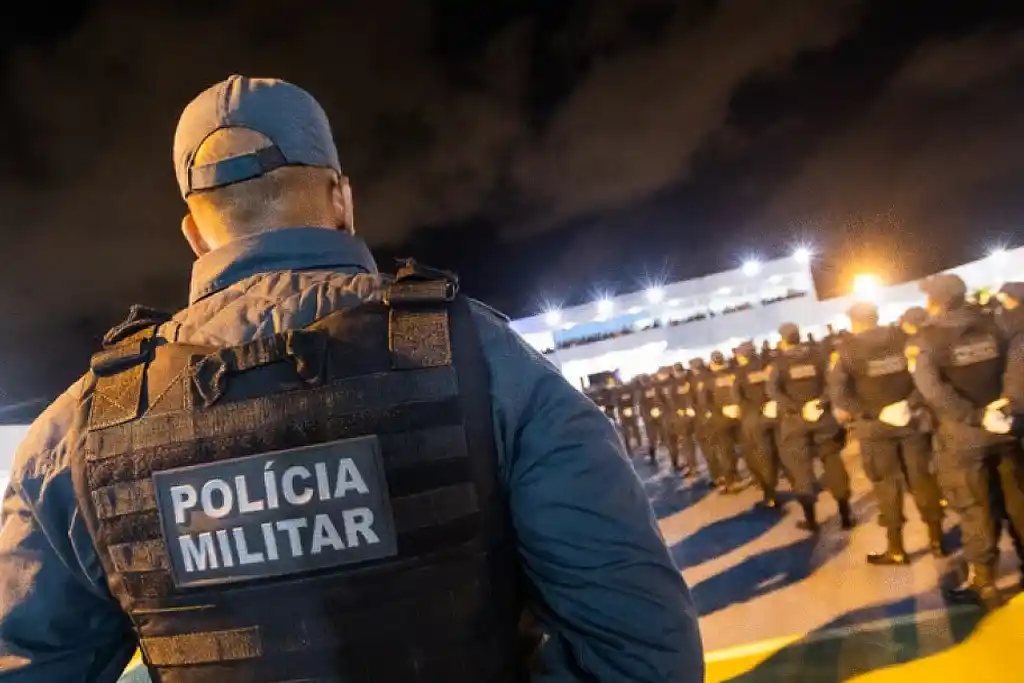 Policial vestido com um colete, em pé na frente de um grupo de soldados