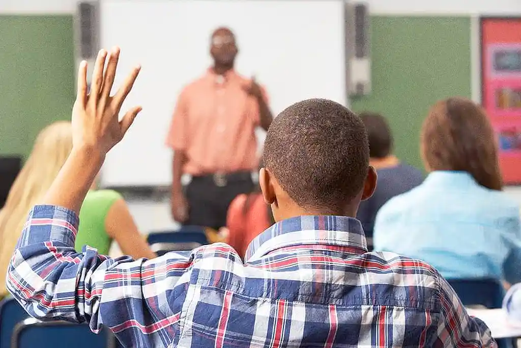 Estudante em primeiro plano e professor negro na sala de aula