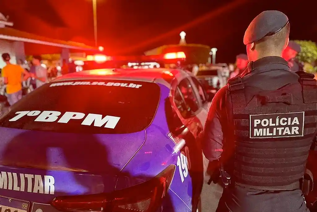 Policial da PMSE ao lado de uma viatura, durante patrulha em um evento festivo