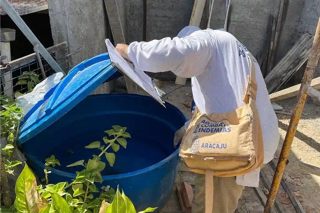 Agente epidemiológico verifica caixa d'água em busca de focos do mosquito Aedes aegypti