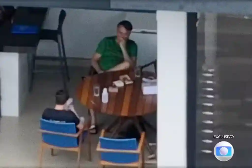 Deputado Nikolas Ferreira usando celular ao lado de Bolsonaro durante visita na prisão domiciliar