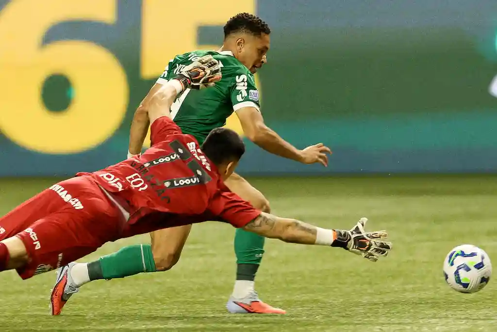 O jogador Vitor Roque, do Palmeiras, chuta para marcar seu gol contra o Santos FC, no Brasileirão 2025