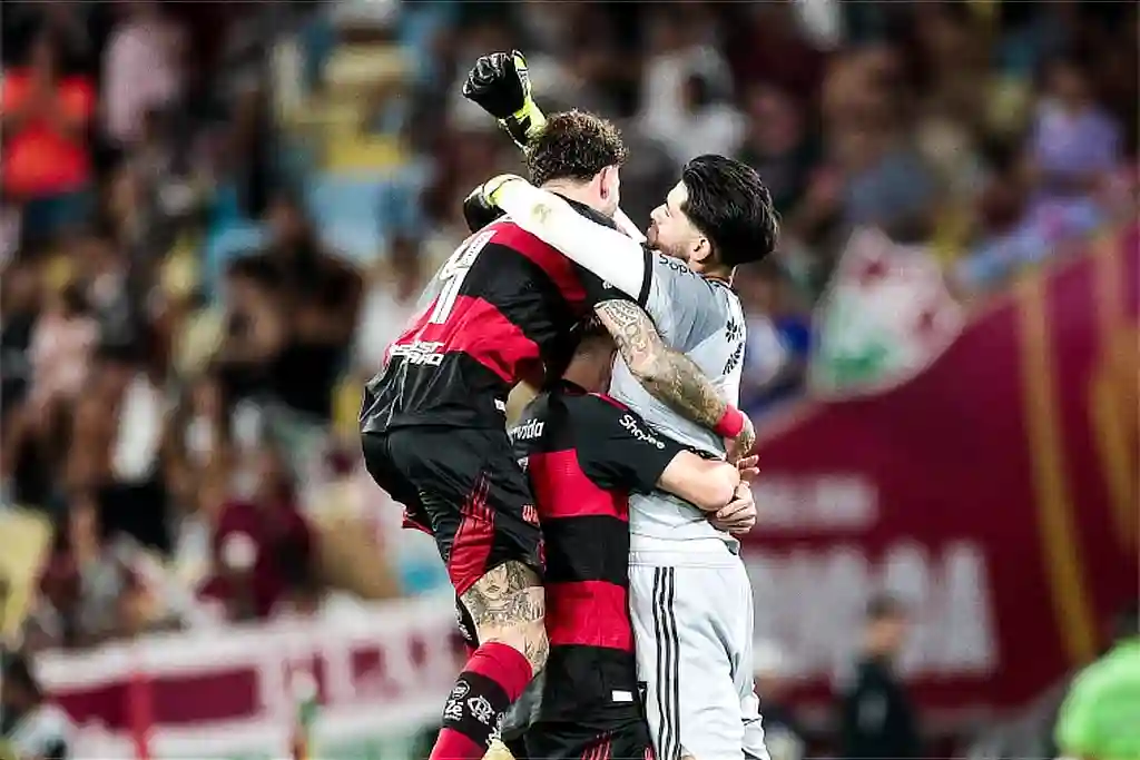 Nos pênaltis, Flamengo vence Flu e é tricampeão carioca 1 Flamengo é Tricampeão no Carioca 2026. Na foto, o Goleiro Rossi é abraçado por companheiros de equipe
