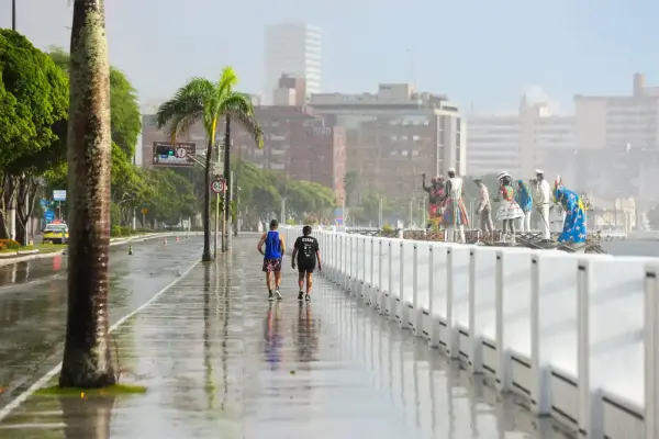 Casal caminhando à beira-mar numa manhã chuvosa em Aracaju
