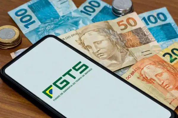 Celular exibindo aplicativo do FGTS com cédulas de Real ao redor