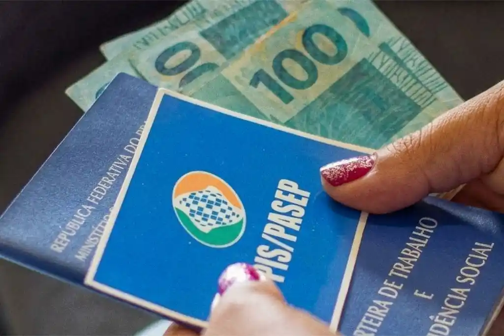 Ex-prefeito sergipano pode ter de devolver R$ 1,75 mi ao município 2 Imagem de mãos segurando carteira de trabalho com dizeres do Pis / Pasep e cédulas de R$ 100