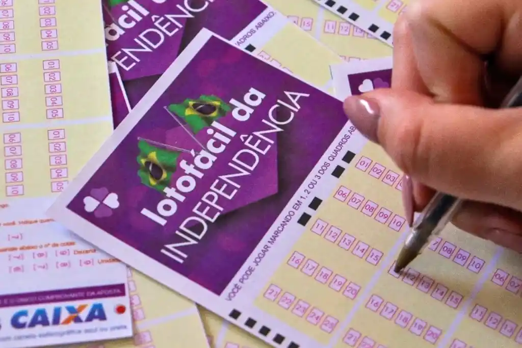 Lotofácil da Independência muda horário do sorteio de R$ 300 mi 1 Pessoa assinalando bilhetes da Lotofácil da Independência